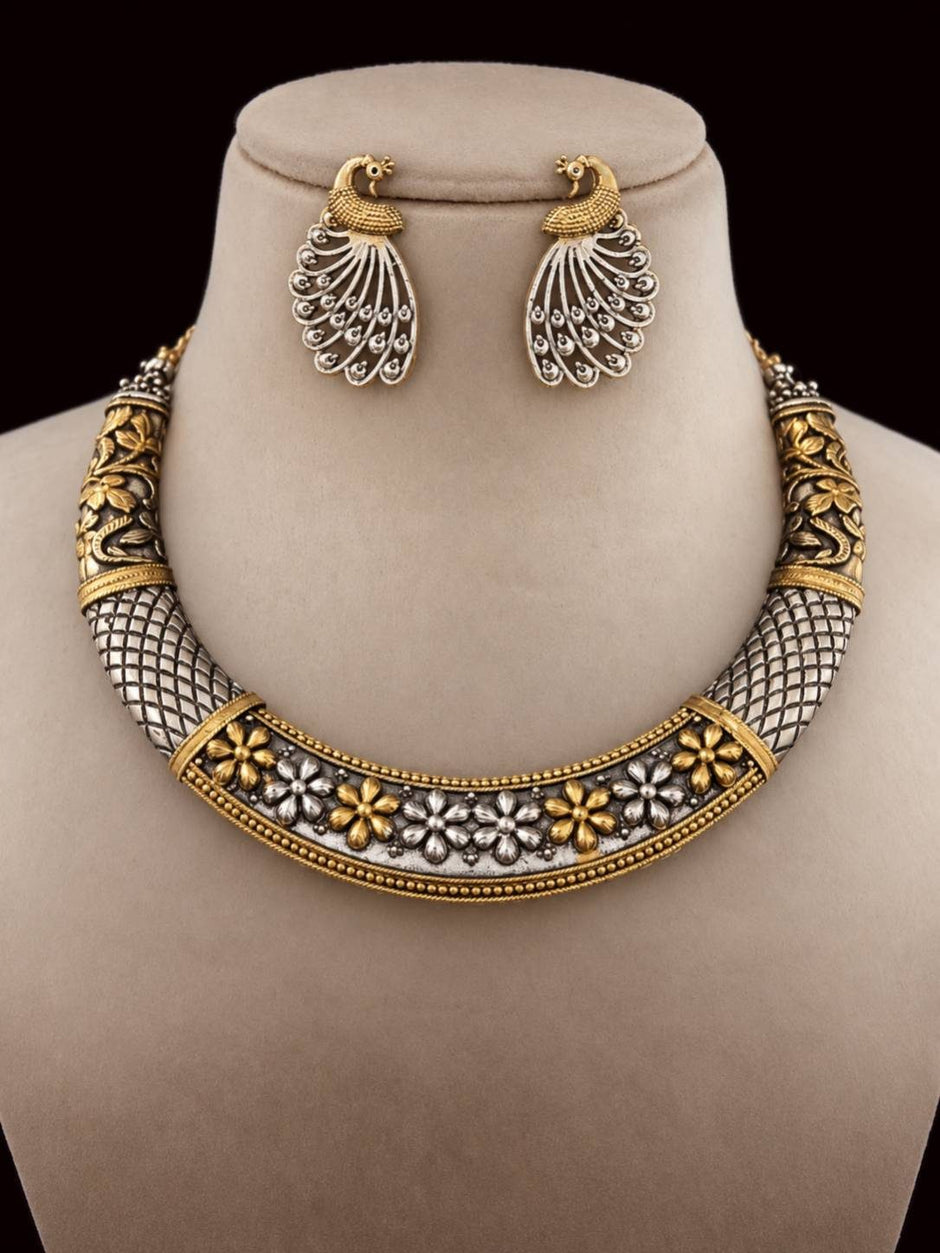 Dual-tone oxidised choker necklace with peacock stud earrings displayed on a jewellery bust against dark background