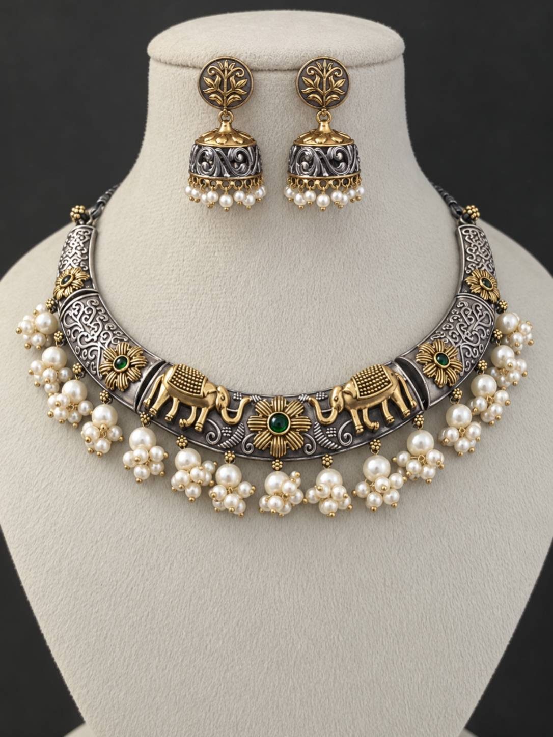 Oxidised dual-tone elephant choker necklace with pearl clusters and jhumka earrings displayed on a jewellery bust