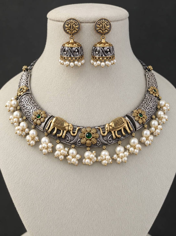 Oxidised dual-tone elephant choker necklace with pearl clusters and jhumka earrings displayed on a jewellery bust