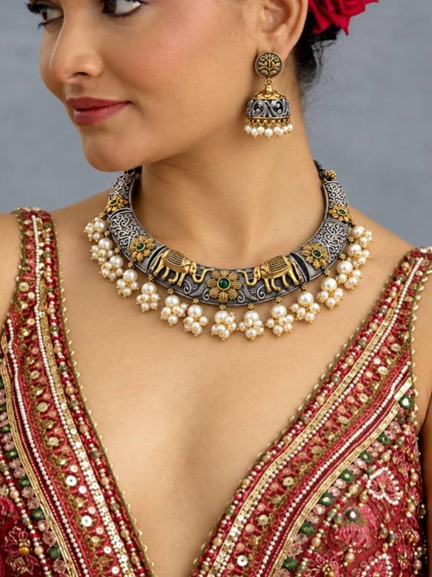 Woman wearing oxidised elephant choker necklace and jhumka earrings styled with an embroidered red bridal lehenga
