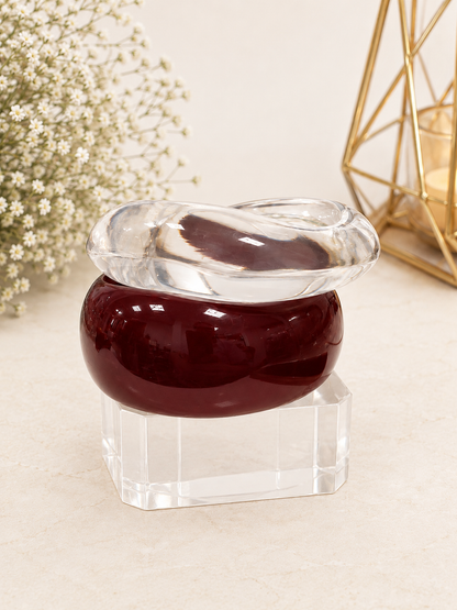 Two stacked acrylic dome bangles, one clear and one maroon, displayed on a crystal block stand