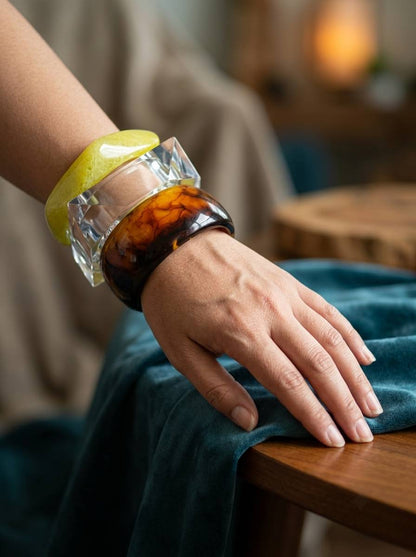 Three resin bangles worn together on a woman's wrist resting on teal velvet fabric