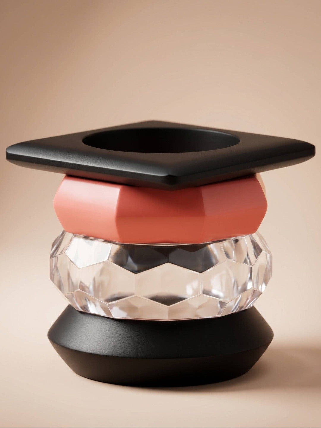 Four acrylic bangles stacked vertically — black square, pink geometric, clear faceted, black domed — on a beige background
