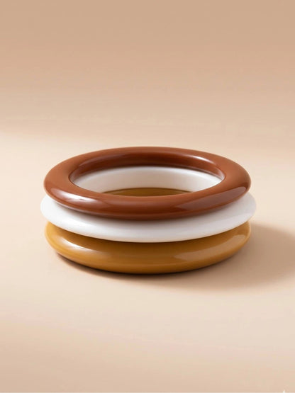 Front-facing view of three resin bangles stacked flat showing terracotta on top, ivory in middle and mustard at the base