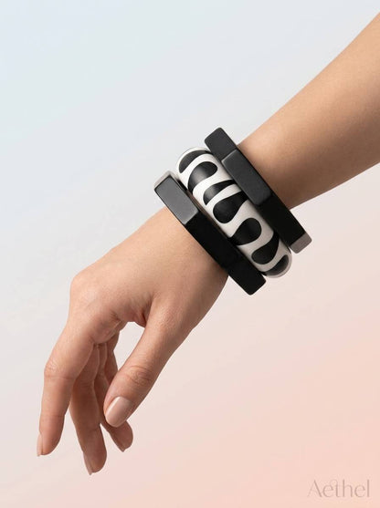 All three resin bangles stacked on a woman's wrist against a soft gradient background