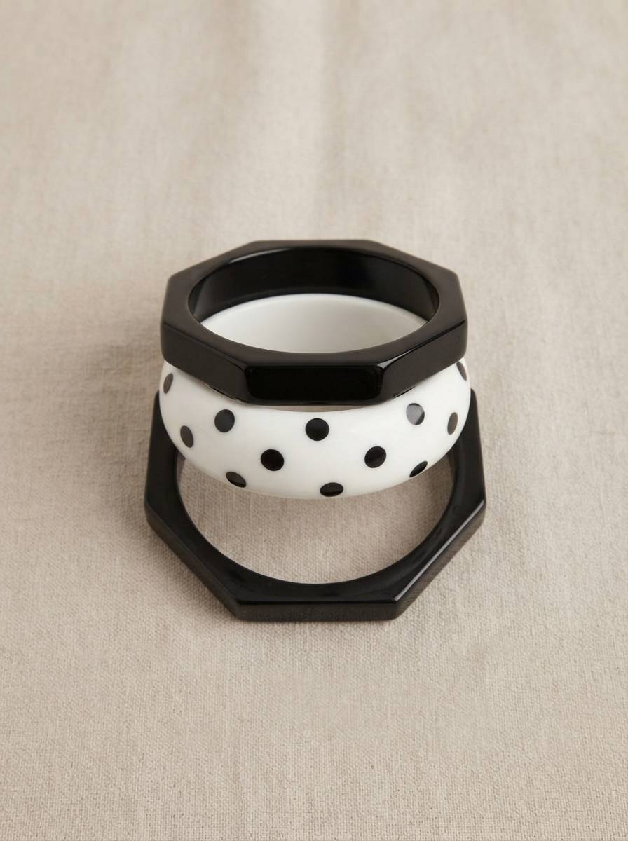 Three-piece resin bangle stack viewed from front on linen background showing octagonal black and round white polka-dot bangles