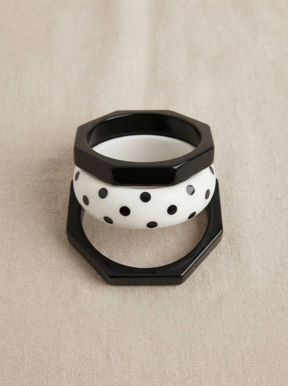 Three-piece resin bangle stack viewed from front on linen background showing octagonal black and round white polka-dot bangles