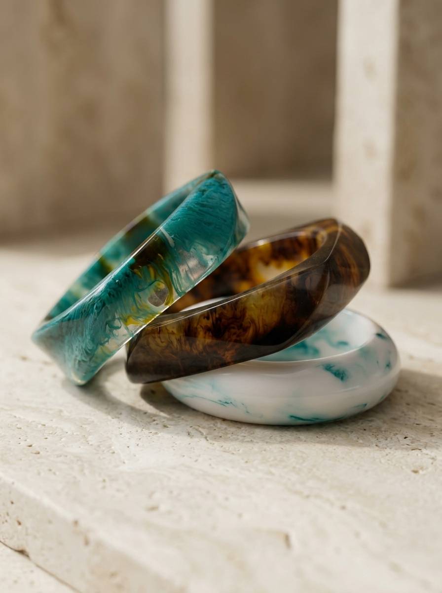 Three resin marble bangles leaning against each other on a white stone surface in natural light