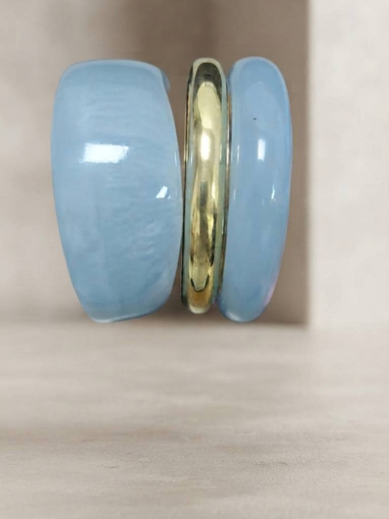 Side profile of three stacked bangles showing the two wide blue resin pieces sandwiching a slim gold-tone metal bangle