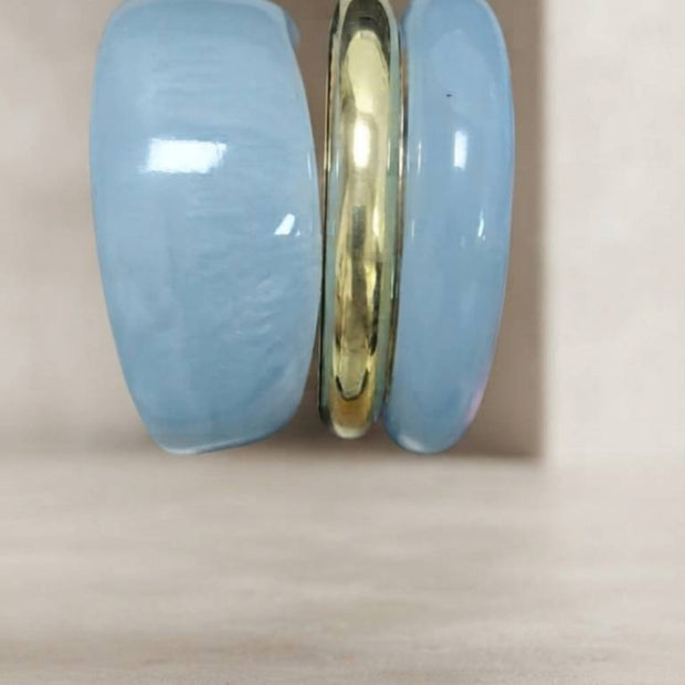 Side profile of three stacked bangles showing the two wide blue resin pieces sandwiching a slim gold-tone metal bangle