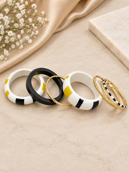 Five individual enamel and gold-tone bangles laid flat in a fan arrangement on a marble surface