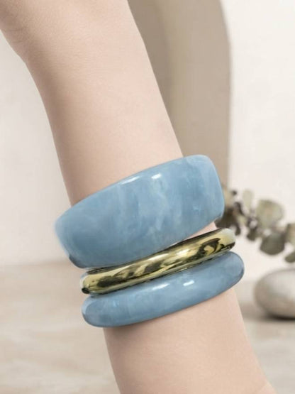 Blue marble resin bangle set with gold-tone band worn on a mannequin wrist against a light background