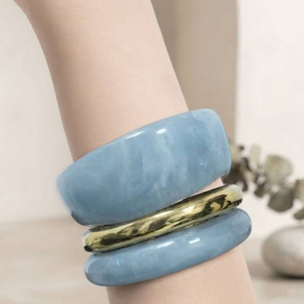 Blue marble resin bangle set with gold-tone band worn on a mannequin wrist against a light background
