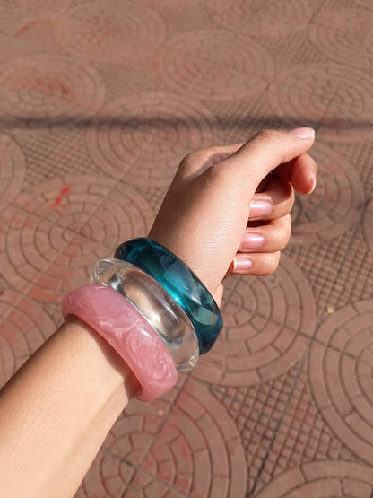 All three resin bangles stacked on a wrist with fist raised against a terracotta patterned floor