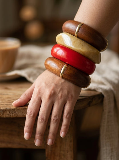 Close-up of all four bangles worn stacked on a woman's wrist resting on a wooden stool