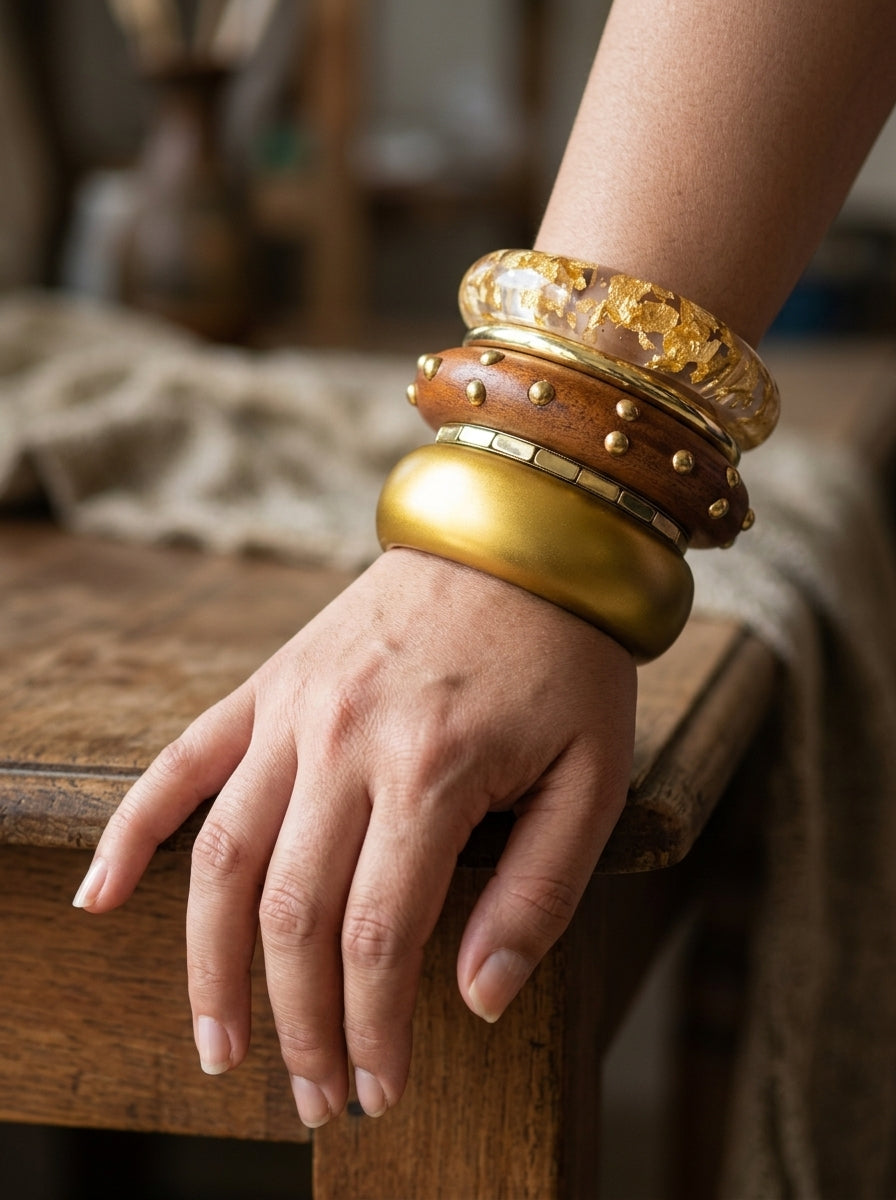 Close-up of all four bangles worn together on a woman's wrist resting on a wooden surface