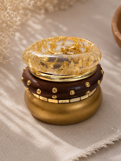 Side angle of the four bangles stacked together on a linen surface with dried flowers in the background