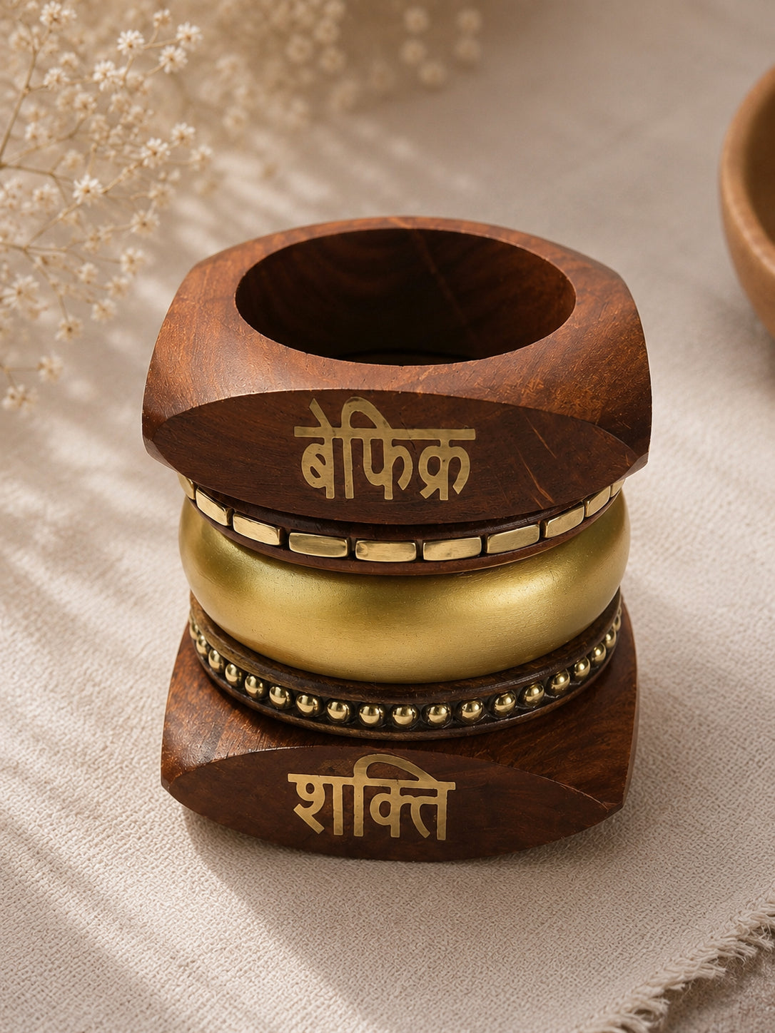 Close-up top view of the full bangle stack showing Befikr wood bangle on top, smooth gold dome bangle in the middle, and Shakti wood bangle at the base