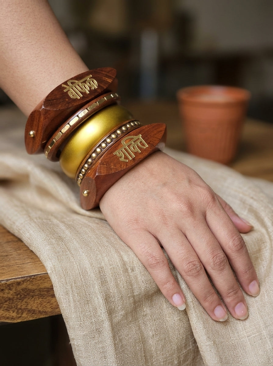 Bangle stack worn on a woman's wrist resting on a linen cloth with a terracotta pot in the background