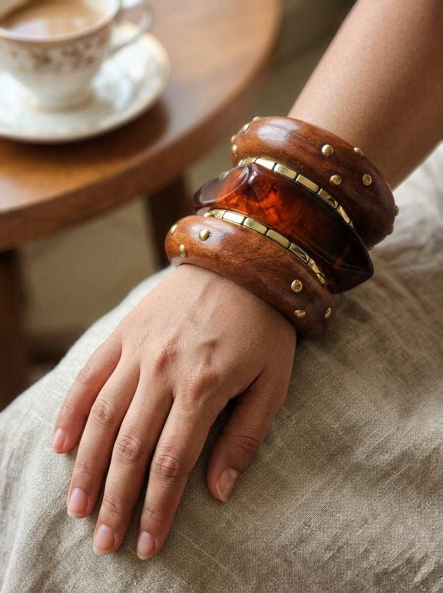 Bangles worn on a woman's wrist resting on linen fabric, with a tea cup on a wooden table in the background
