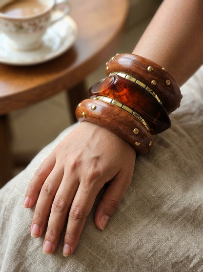 Bangles worn on a woman's wrist resting on linen fabric, with a tea cup on a wooden table in the background