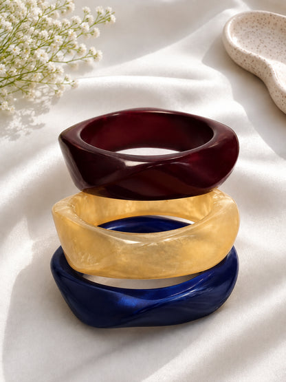 Chunky resin bangles stacked on white fabric with baby's breath flowers in the background
