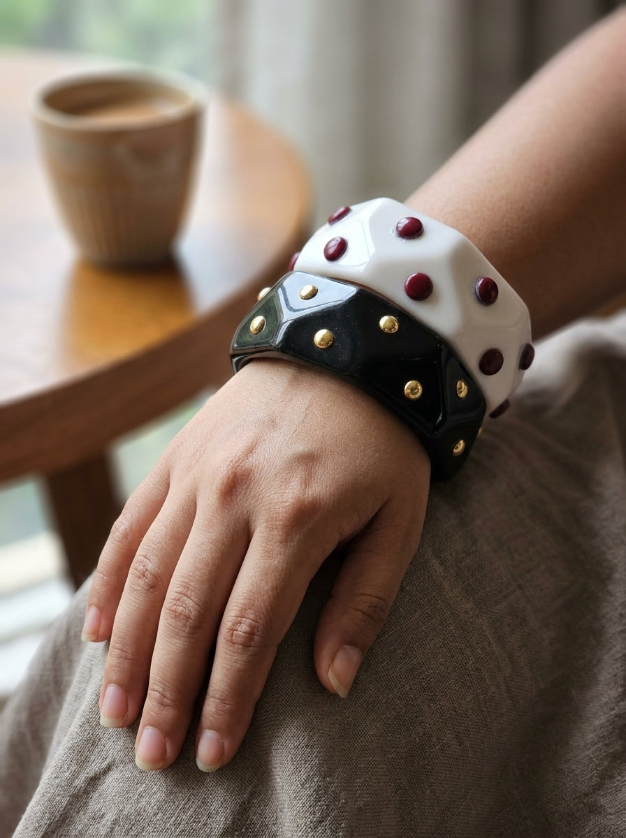 Both studded resin cuff bangles worn together on a woman's wrist against linen fabric