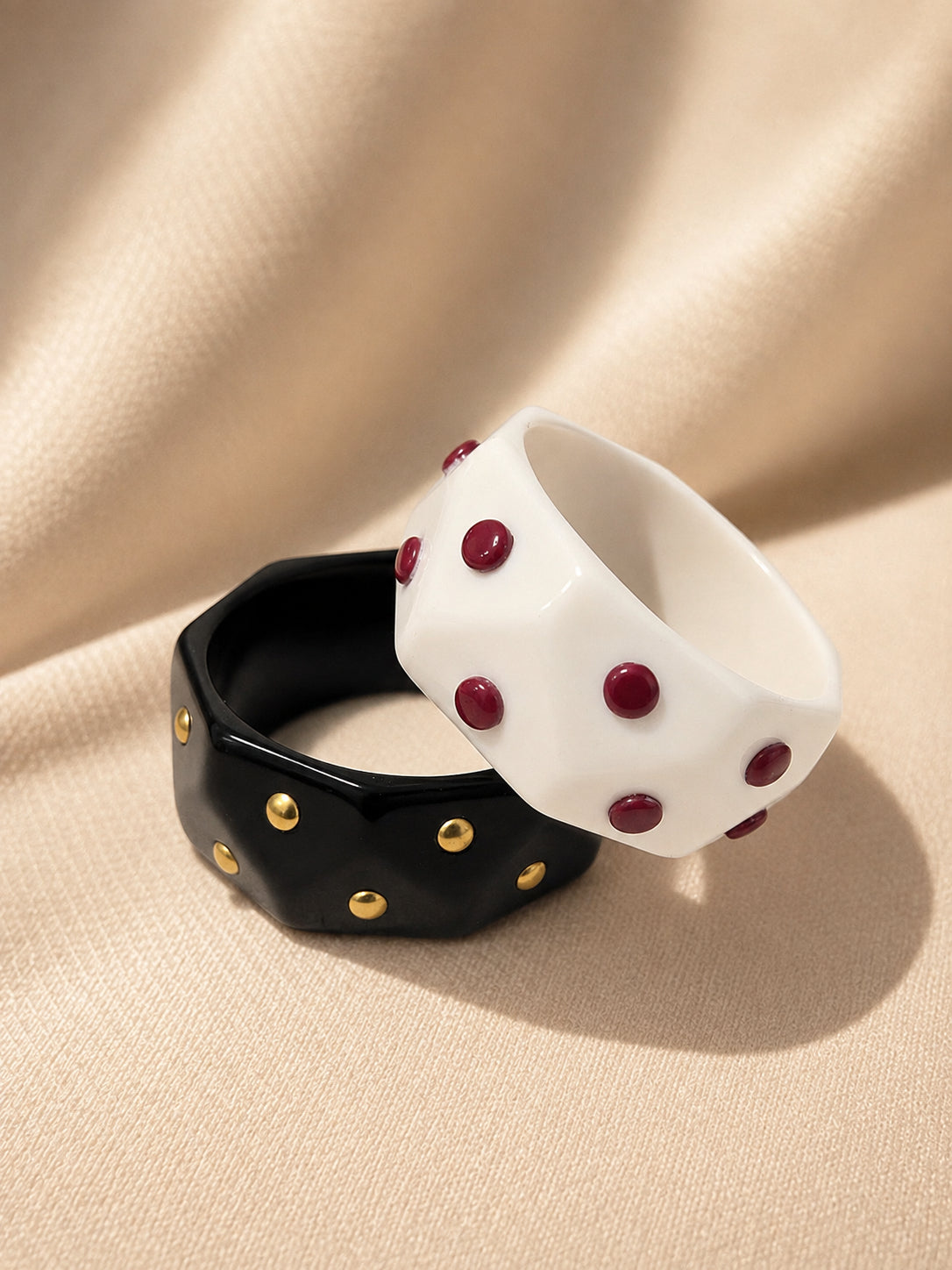 Black and white geometric resin cuff bangles with dome studs on cream fabric background