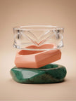 Clear acrylic, coral-pink and marbled green resin bangles stacked vertically on a beige studio background