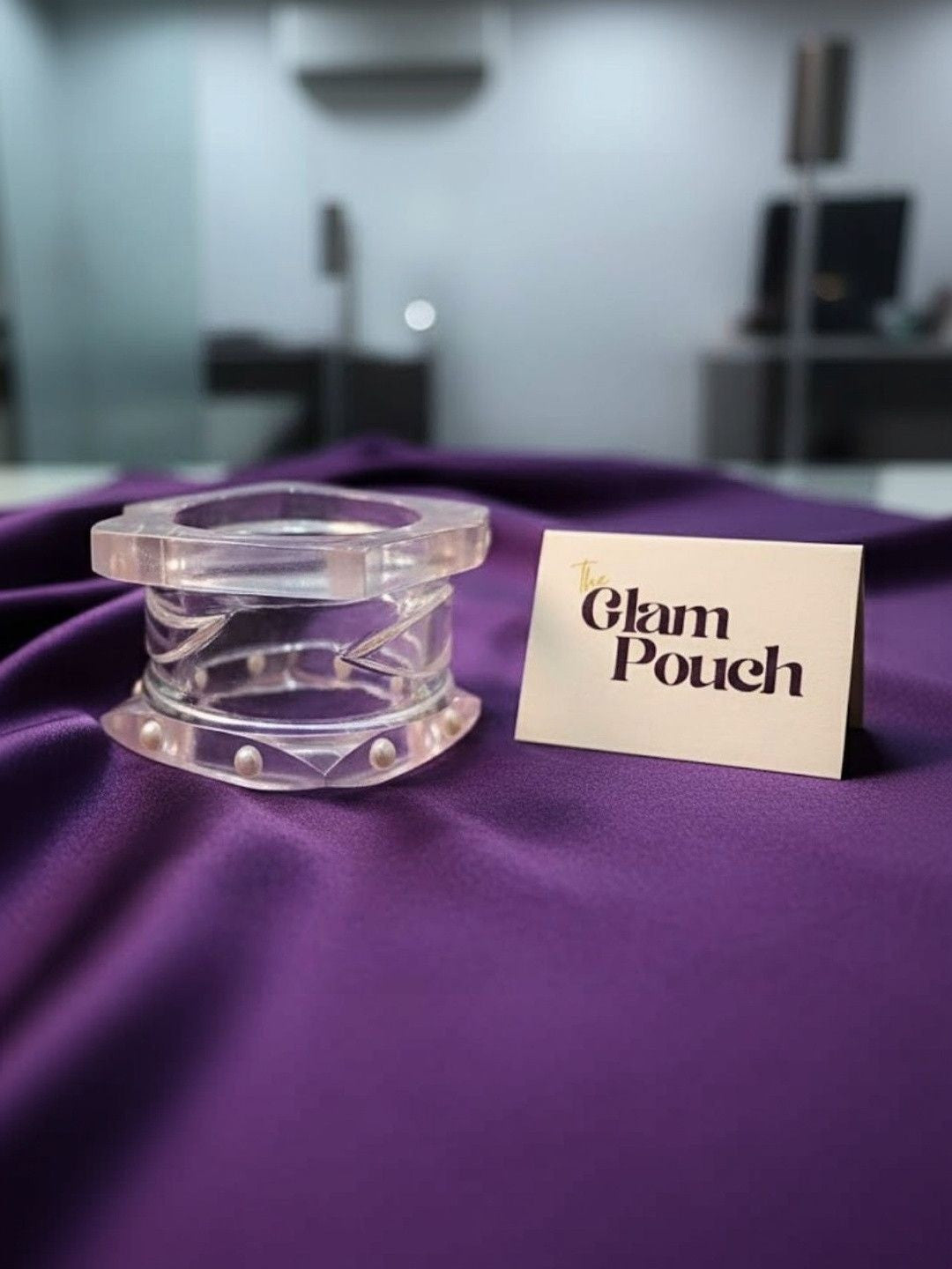 Clear acrylic bangles with faux pearl detail displayed on purple silk beside a Glam Pouch brand card