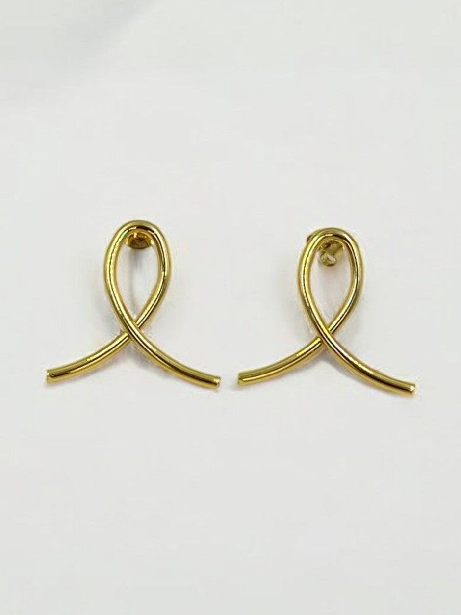 Close-up of gold-plated ribbon loop stud earrings on a white surface showing push-back posts
