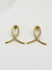 Close-up of gold-plated ribbon loop stud earrings on a white surface showing push-back posts
