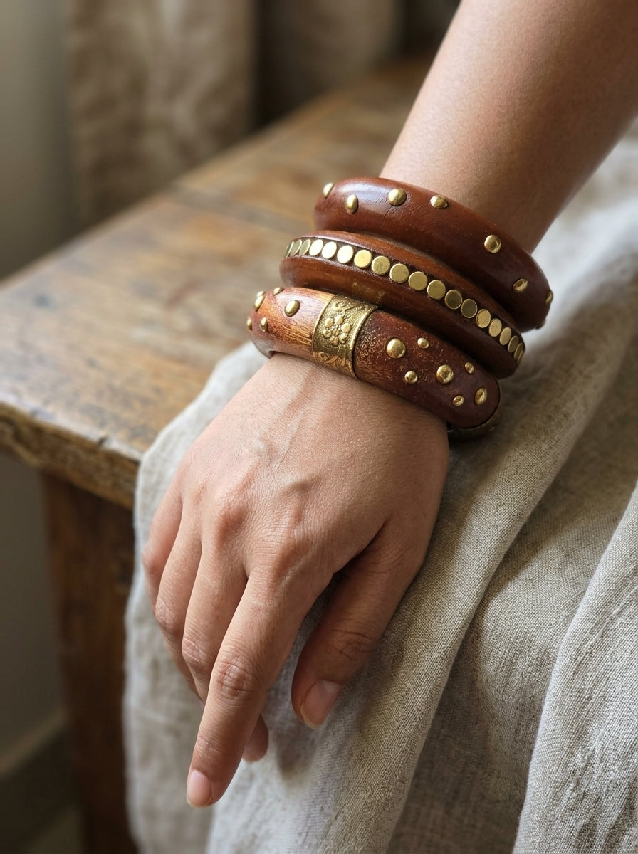 All three wooden bangles with brass detailing stacked and worn on a woman's wrist over a linen sleeve