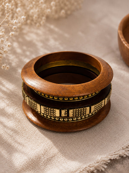 Four bangles stacked together on a textured beige cloth showing antique brass dot and block detailing clearly