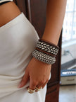 Woman wearing full bangle stack on wrist with white outfit, showing braided and ball-stud oxidised silver bangles with wood bangles