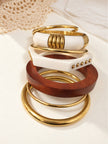 Gold-toned mixed-media bangle stack laid flat on a white surface showing all five pieces