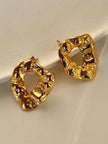 Pair of gold-plated open studs with hammered molten texture displayed on a cream surface