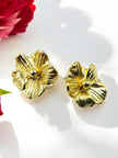 Pair of gold-plated flower stud earrings with ridged petals on white background near a red rose