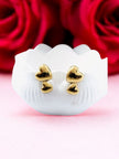 Pair of gold-plated double heart stud earrings displayed on white shell dish with red roses in background