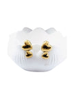 Close-up of polished gold double heart stud earrings on white shell-shaped jewellery holder against white background