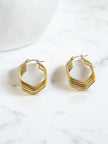 Pair of gold-plated geometric hoop earrings with ridged layered texture on a white marble surface