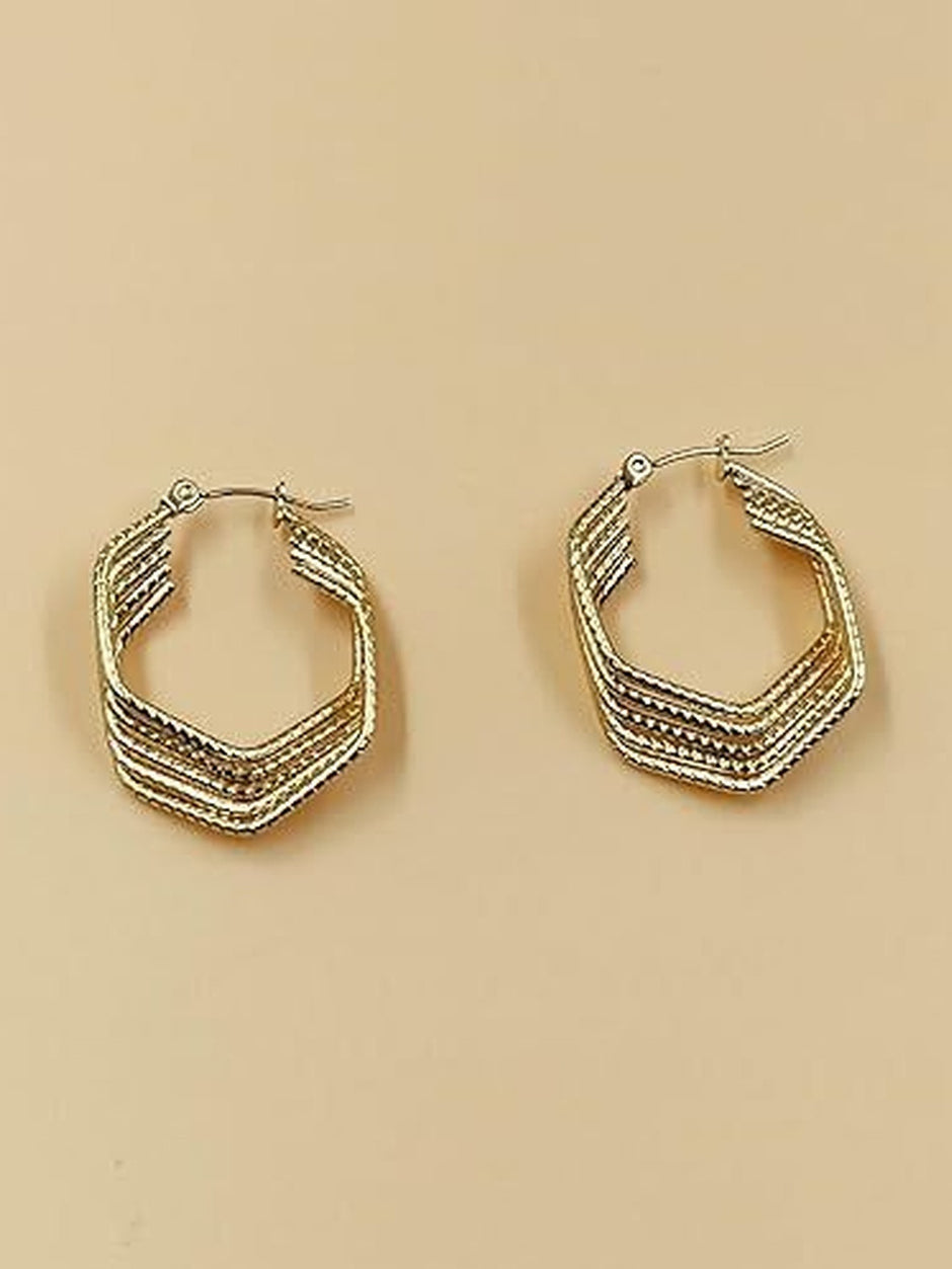 Two gold-tone angular hoop earrings with multi-row ridged design displayed on a beige background