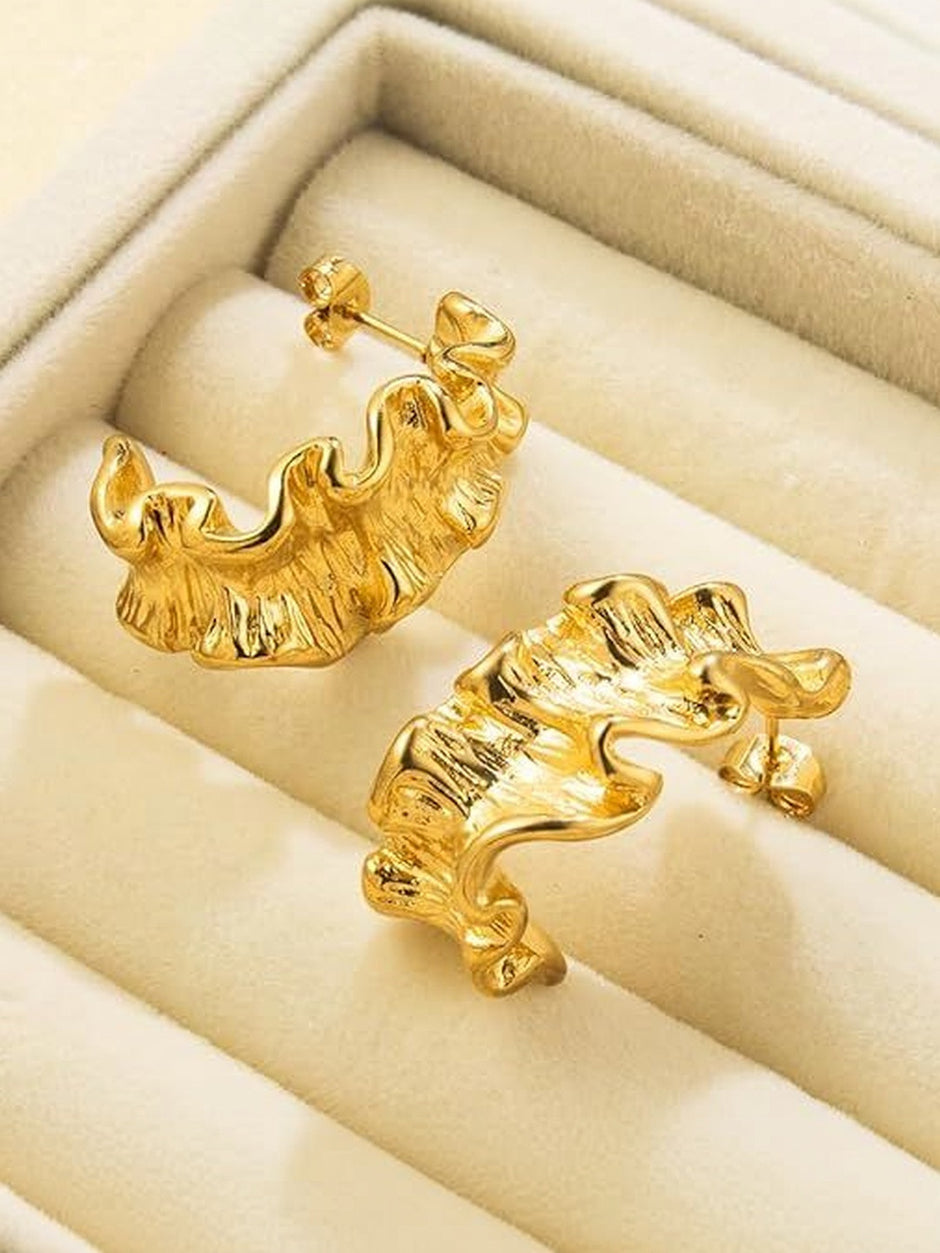 Two gold ruffled hoop earrings displayed inside an open cream velvet jewellery box showing stud backs