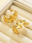 Two gold ruffled hoop earrings displayed inside an open cream velvet jewellery box showing stud backs