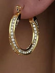 Close-up of a single gold crystal hoop earring worn on a model's earlobe, showing full sparkle and fit