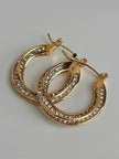 Pair of gold-plated crystal hoops stacked overlapping on grey surface, showing depth and width of the band