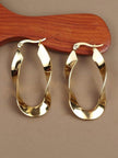 Two gold-tone twisted ribbon hoop earrings displayed on a warm wooden prop