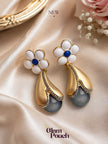 Pair of gold-plated floral drop earrings with white enamel petals and grey faux-pearl pendant on satin fabric