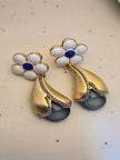Both gold-plated floral earrings laid flat on white surface showing cobalt blue enamel centre and bead detailing