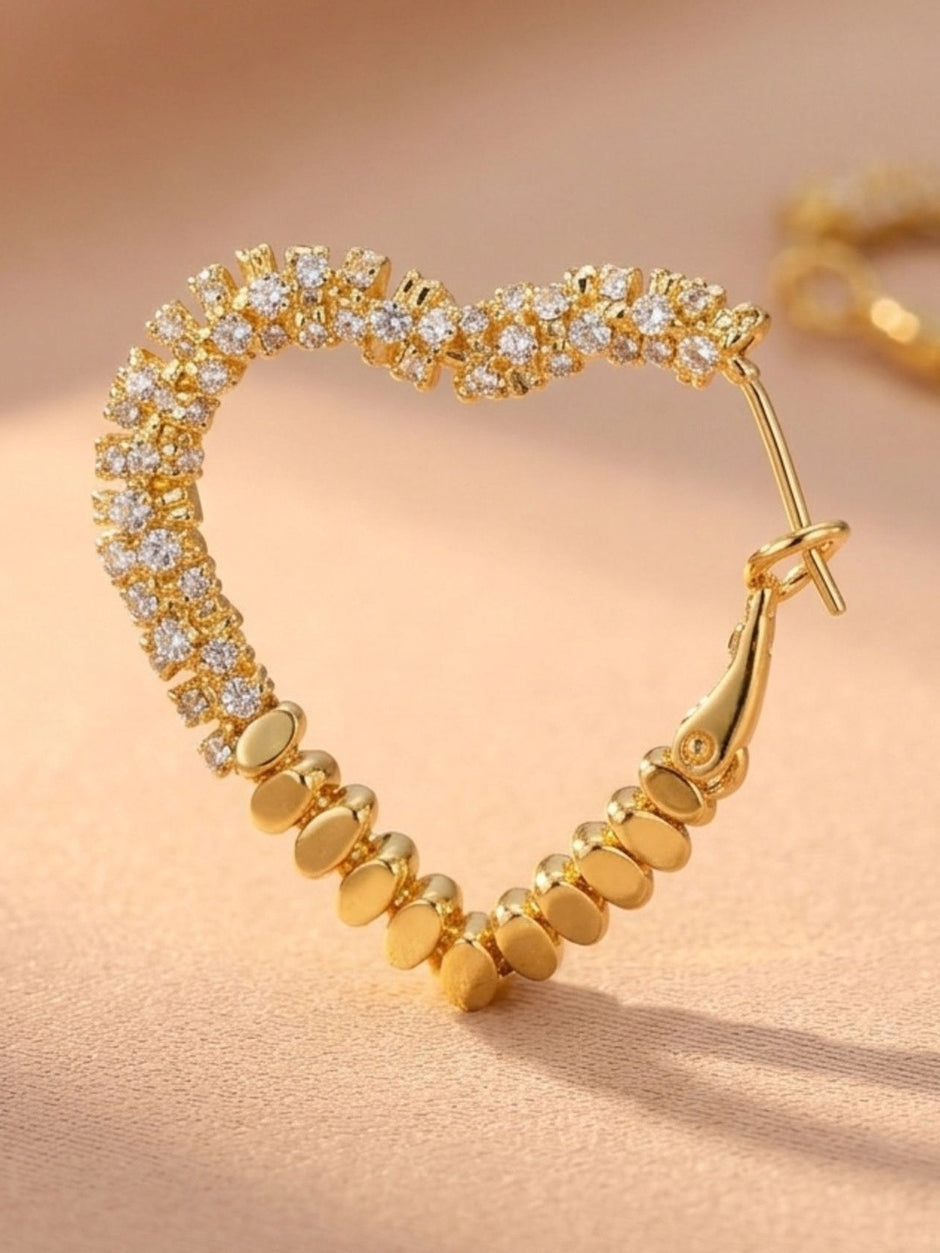Close-up of single gold heart hoop earring showing cubic zirconia stones and gold bead detailing